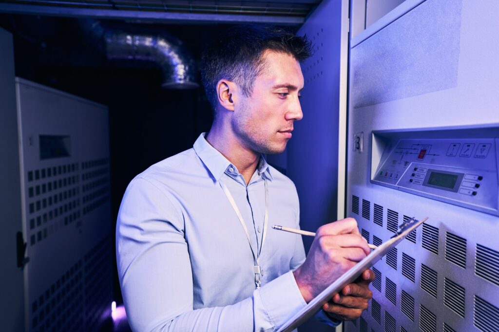 Male technician monitoring equipment performance in data center